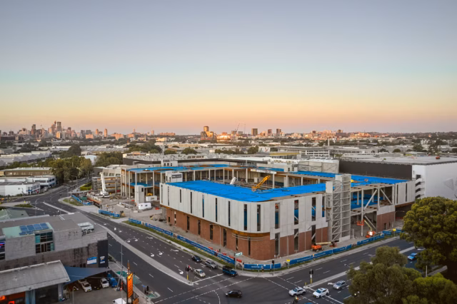 Professional drone photography of a commercial construction site and urban development project. High resolution aerial image showcasing industrial architecture and city planning during sunset